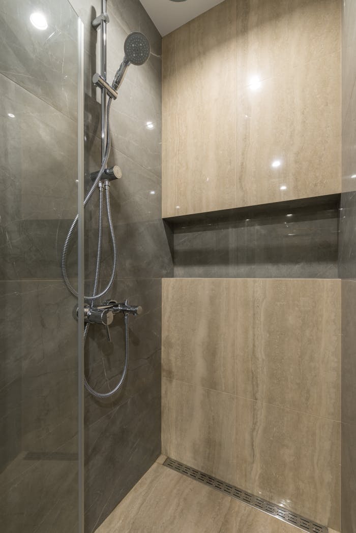 Elegant bathroom shower with chrome fixtures and marble tiles, showcasing modern minimalist design.